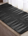 Black bath mat with geometric pattern on a bathroom floor.