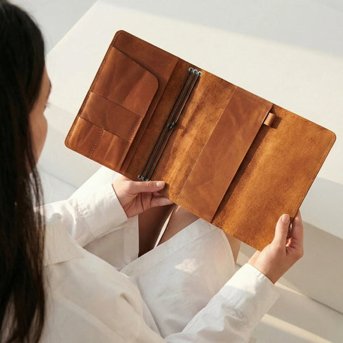 Person holding a brown leather wallet against a neutral background