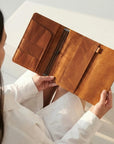Person holding a brown leather wallet against a neutral background