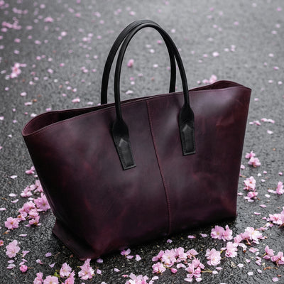 Purple tote bag on a gray surface with pink flower petals