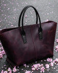 Purple tote bag on a gray surface with pink flower petals