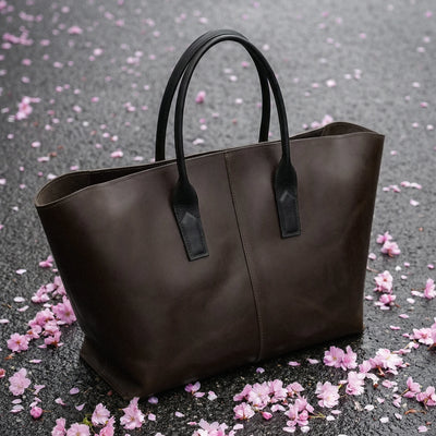 Brown tote bag on a gray surface with pink flower petals
