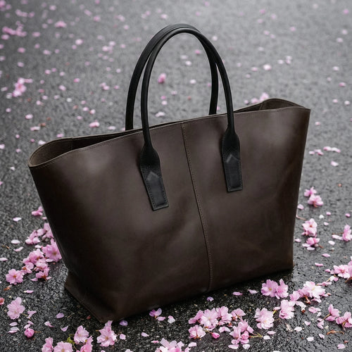 Brown tote bag on a gray surface with pink flower petals