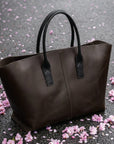Brown tote bag on a gray surface with pink flower petals