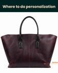 Brown leather tote bag with black handles on a white background
