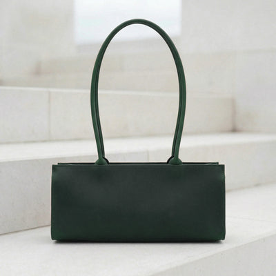 Green handbag on a white surface with a light gray background