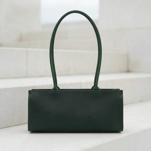 Green handbag on a white surface with a light gray background