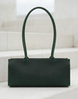 Green handbag on a white surface with a light gray background