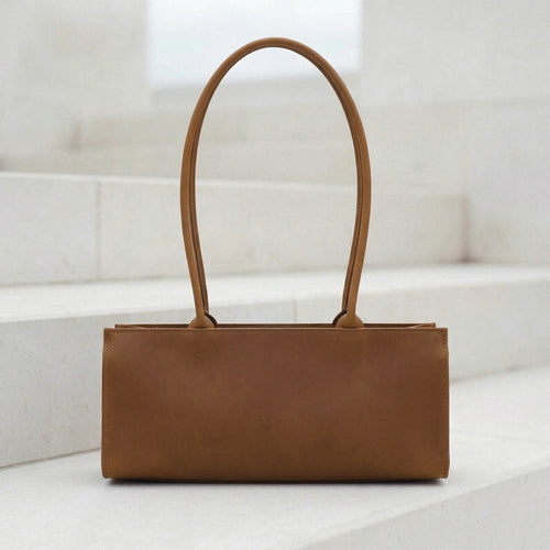 Brown leather handbag on a white surface with a light background
