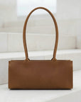 Brown leather handbag on a white surface with a light background