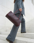 Person in gray suit holding a maroon bag on stone steps