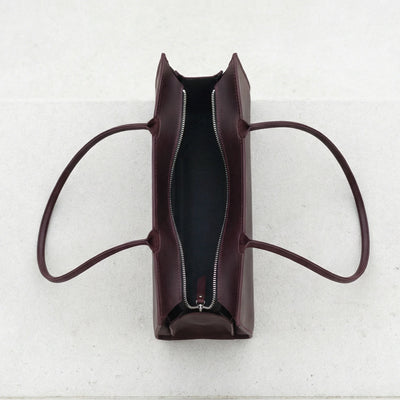 Brown leather handbag with a zipper on a light gray background
