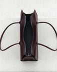 Brown leather handbag with a zipper on a light gray background