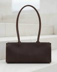 Brown leather handbag on a white surface with a light background