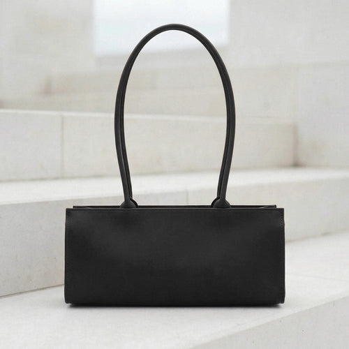 Brown leather handbag on a white surface with a light background