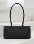 Brown leather handbag on a white surface with a light background