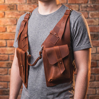 Person wearing a brown leather backpack against a brick wall.
