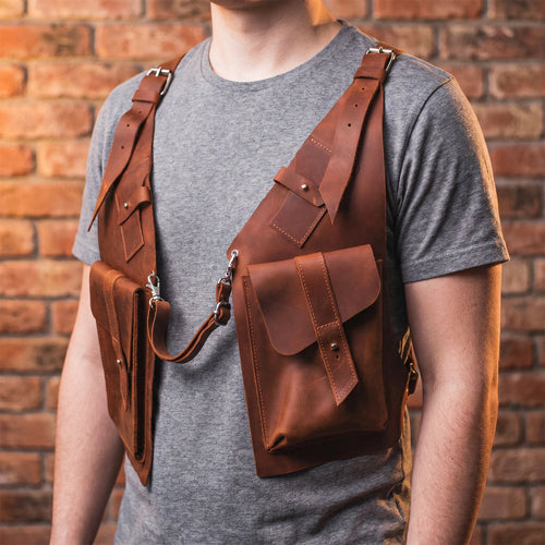 Person wearing a brown leather backpack against a brick wall.