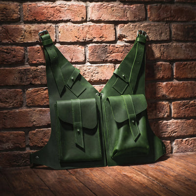 Two green leather bags against a brick wall.