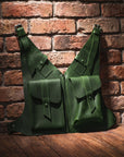 Two green leather bags against a brick wall.