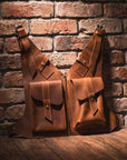 Two brown leather bags against a brick wall.