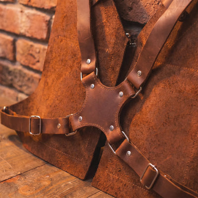 Brown leather harness with metal studs against a brick wall.