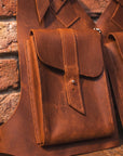 Brown leather pouches against a brick wall background
