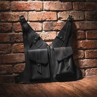 Two black leather bags against a brick wall.